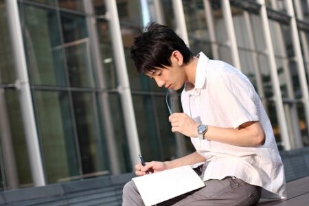 casual asian businessman texting on his book casual asian businessman texting on his book